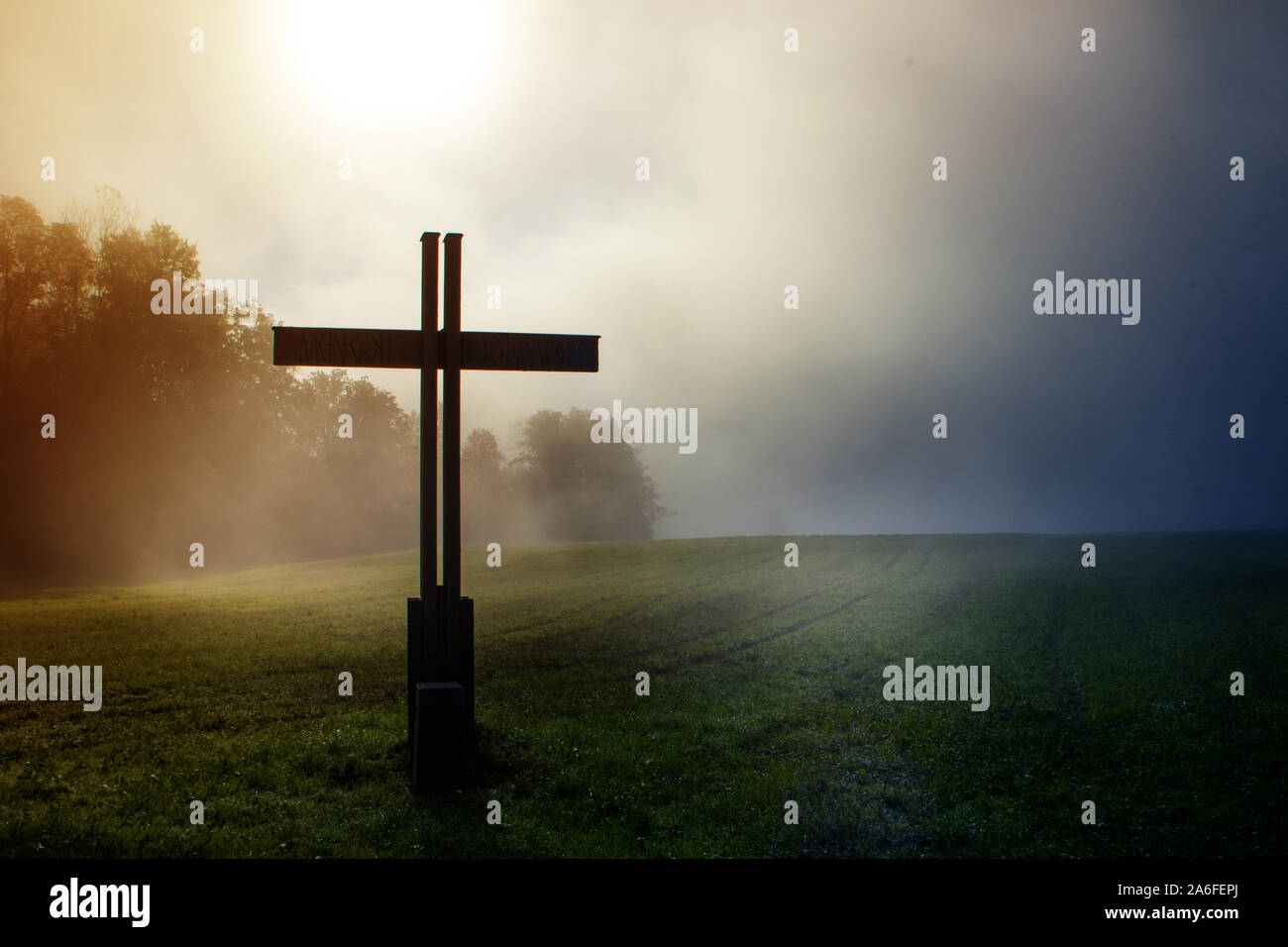 Croce nel paese durante una nebbia morging mistica e impostazione Foto Stock