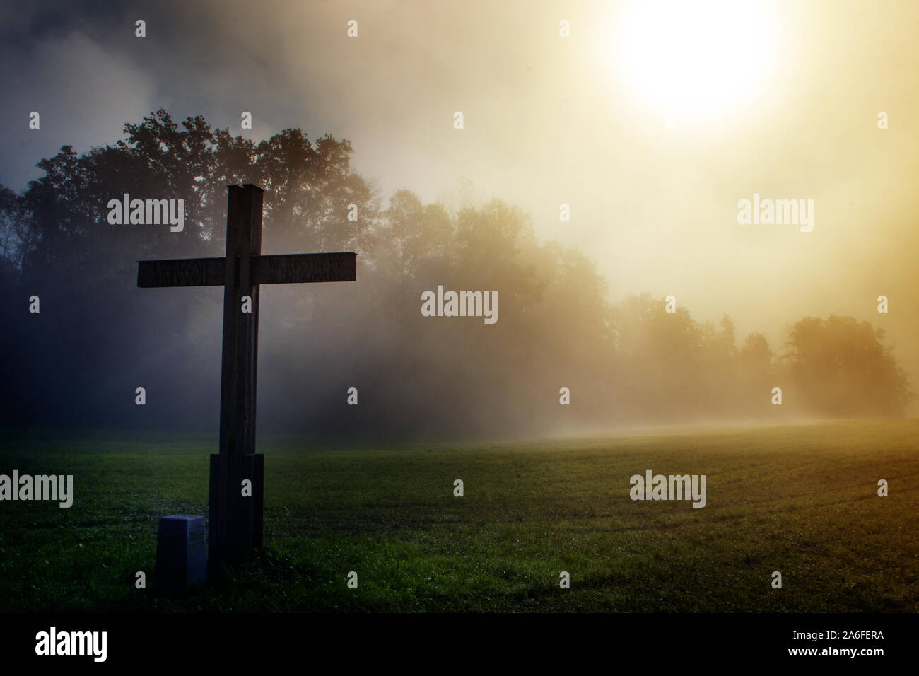 Croce nel paese durante una nebbia morging mistica e impostazione Foto Stock