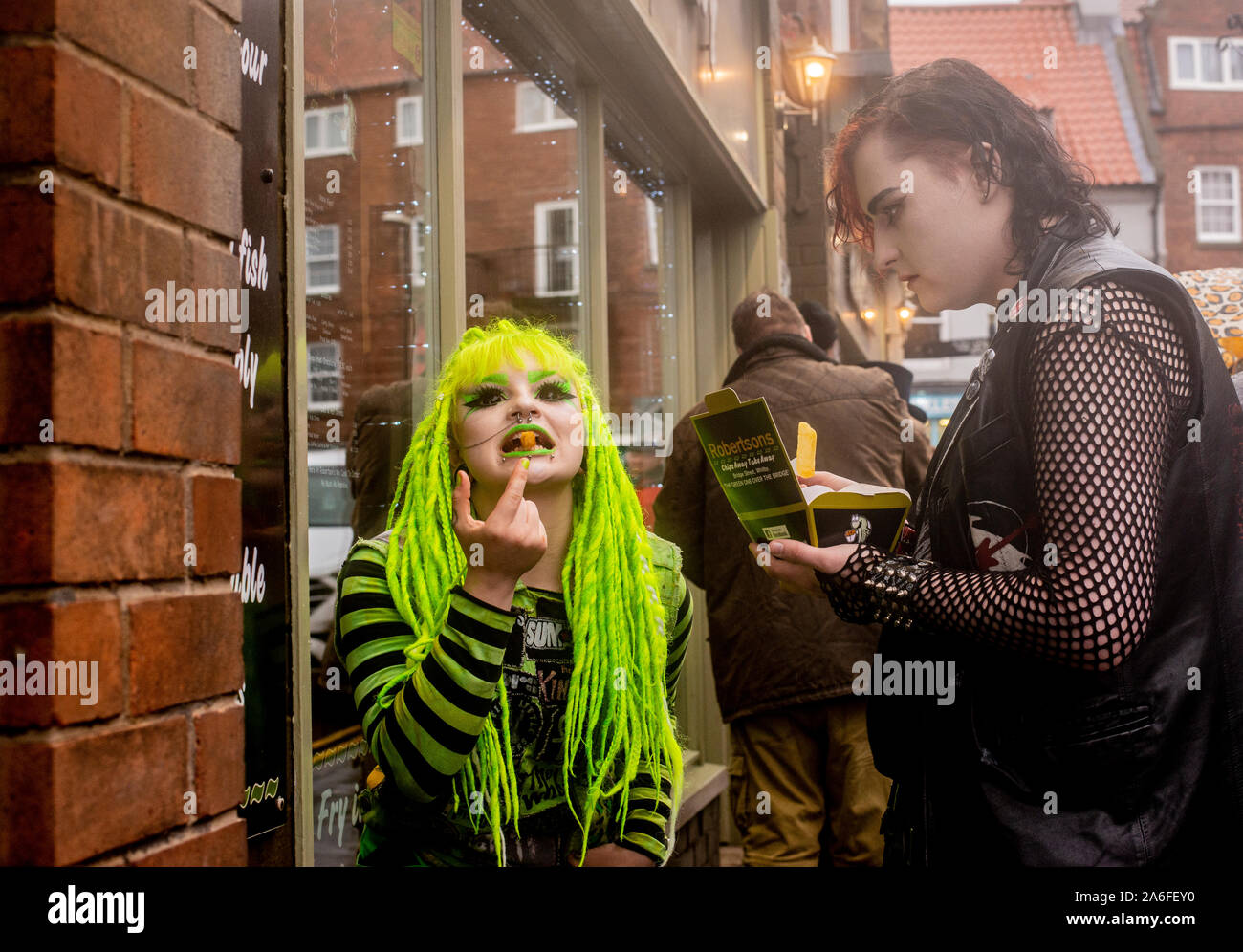 Goth di giovane donna con i capelli verdi mangiare chip, Whitby Goth Festival Weekend, Whitby, North Yorkshire, Regno Unito, 26 Ottobre 2019 Foto Stock