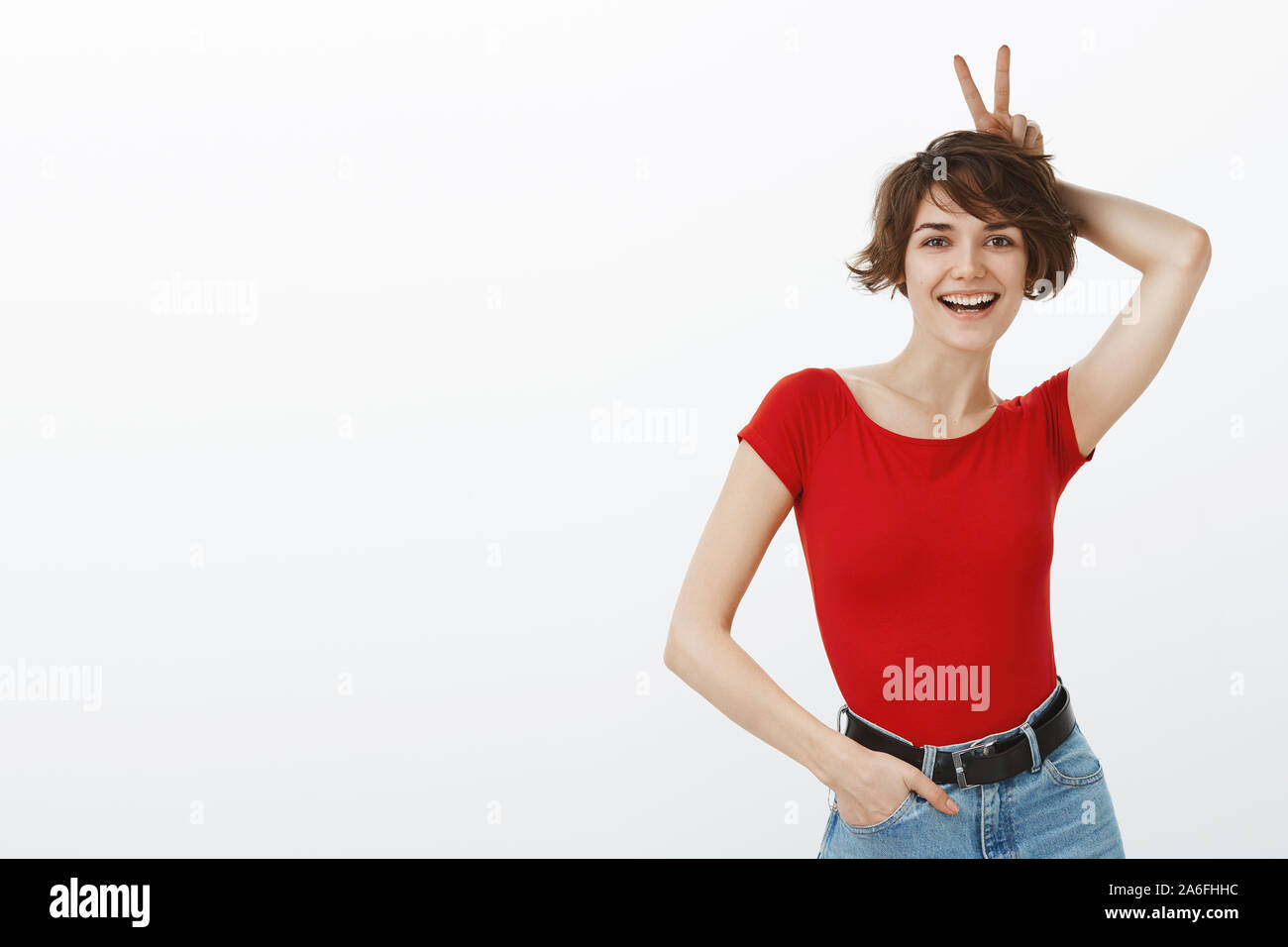 Silly offerta allettante cheeky unione brunette corto pixie haircut visualizza bunny orecchie dita sorridendo felice deliberando divertente giocoso ottimista positiva Foto Stock