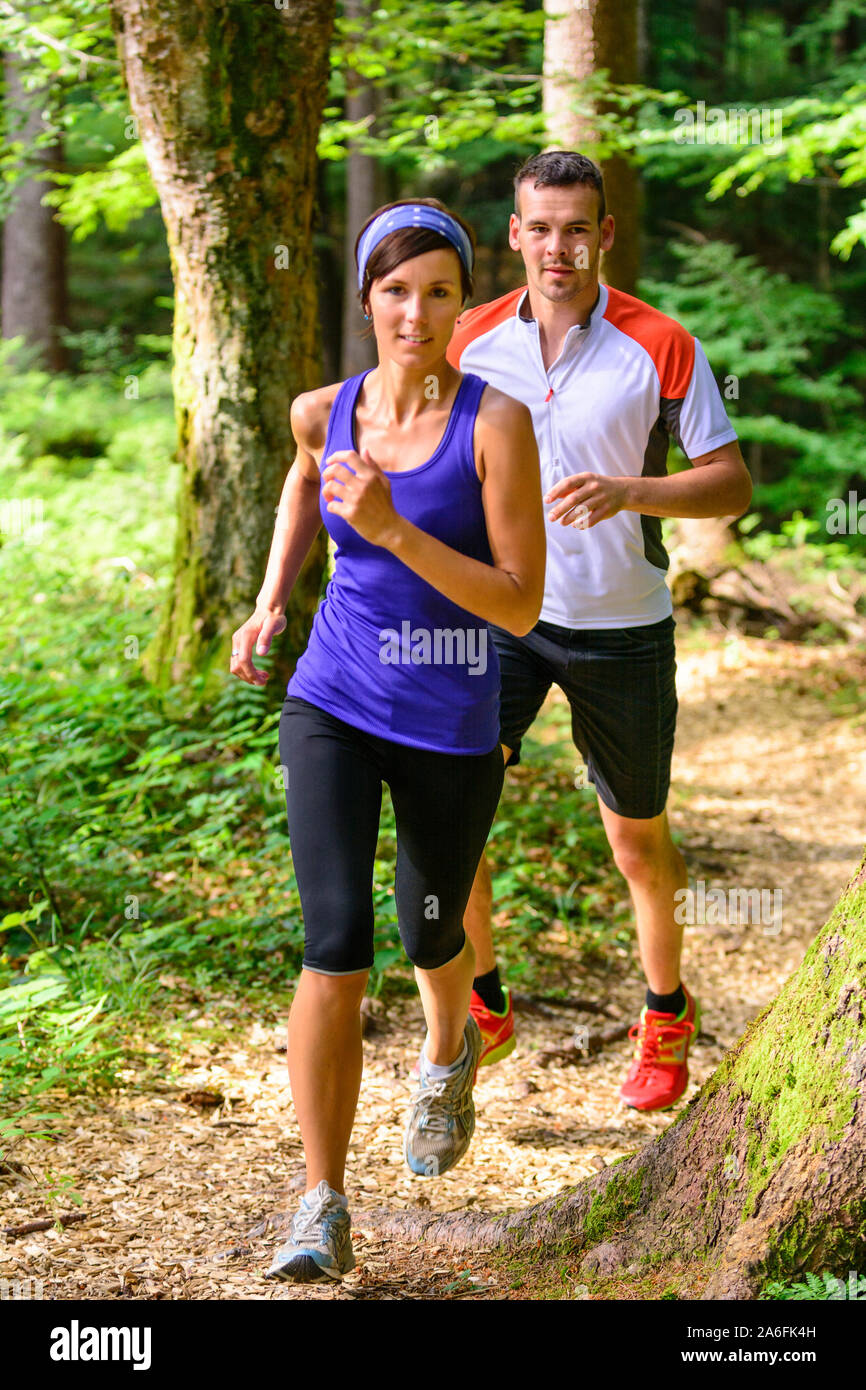 Coppia giovane jogging nella foresta - faticoso allenamento in estate Foto Stock