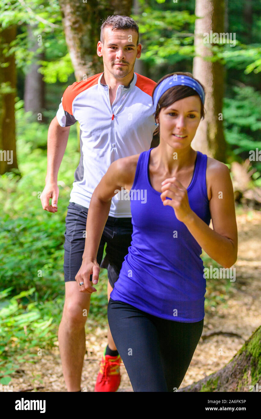 Coppia giovane jogging nella foresta - faticoso allenamento in estate Foto Stock