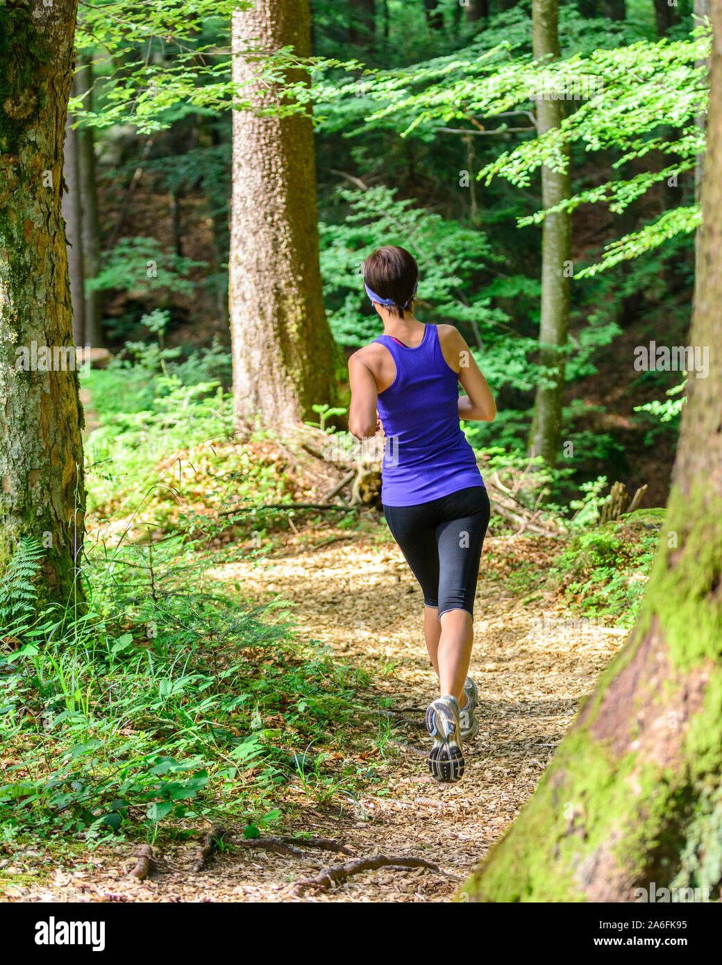 Giovane jogging nella foresta - faticoso allenamento in estate Foto Stock