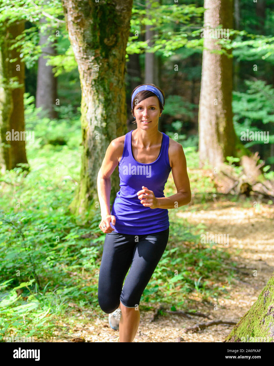 Giovane jogging nella foresta - faticoso allenamento in estate Foto Stock