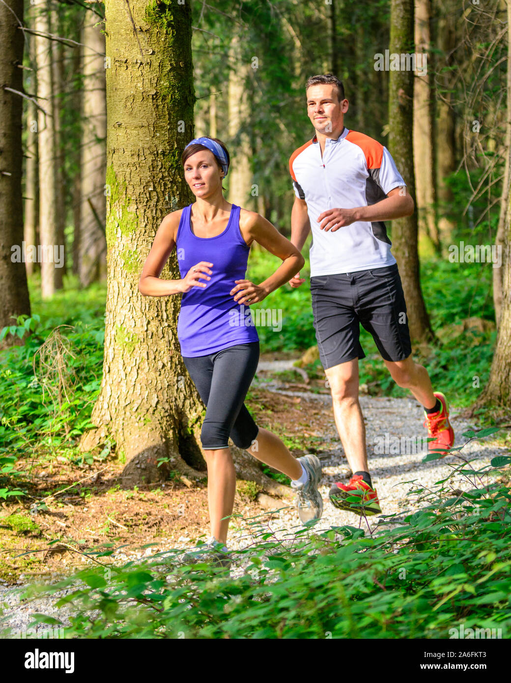 Coppia giovane jogging nella foresta - faticoso allenamento in estate Foto Stock