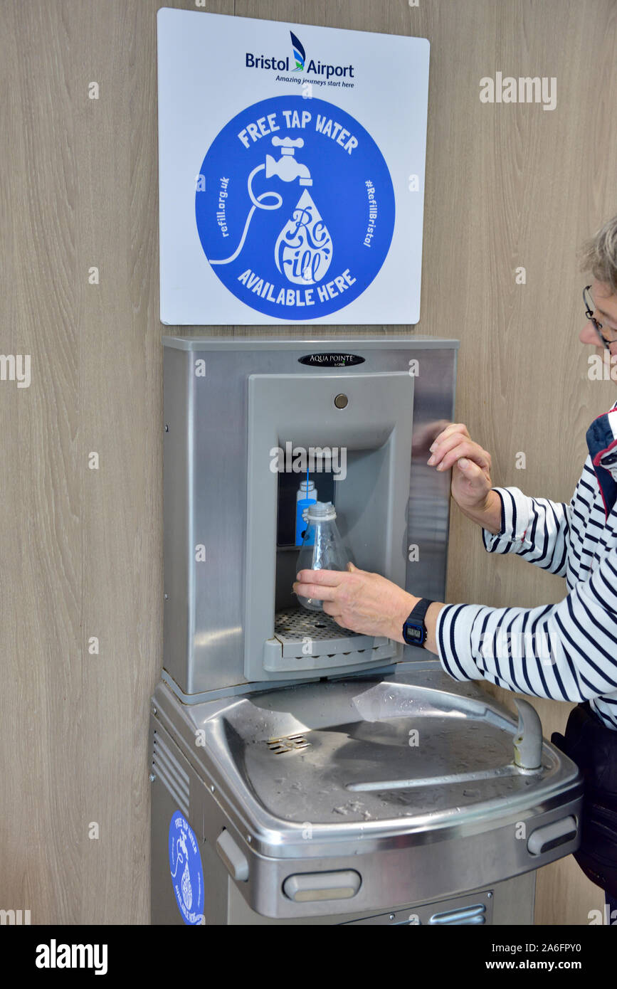La donna il rifornimento di acqua in bottiglia in acqua di rubinetto fontana, Bristol Water presso l'aeroporto di Bristol, Regno Unito Foto Stock