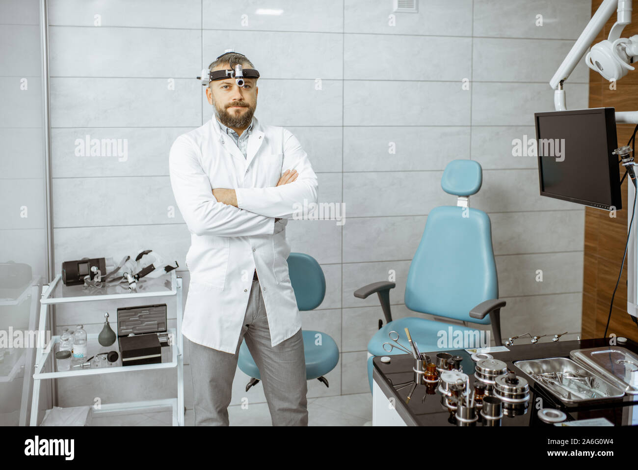 Ritratto di un senior otolaryngologist in piedi in ufficio medico con ENT workstation e per apparecchiature di diagnostica Foto Stock