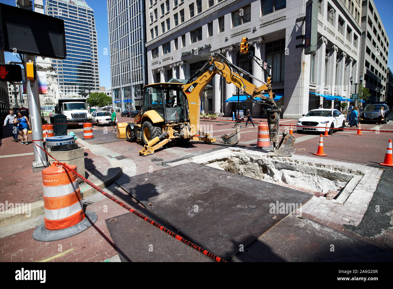 Escavatore cat scava in strada in centro città per utility Indiana Indianapolis USA Foto Stock