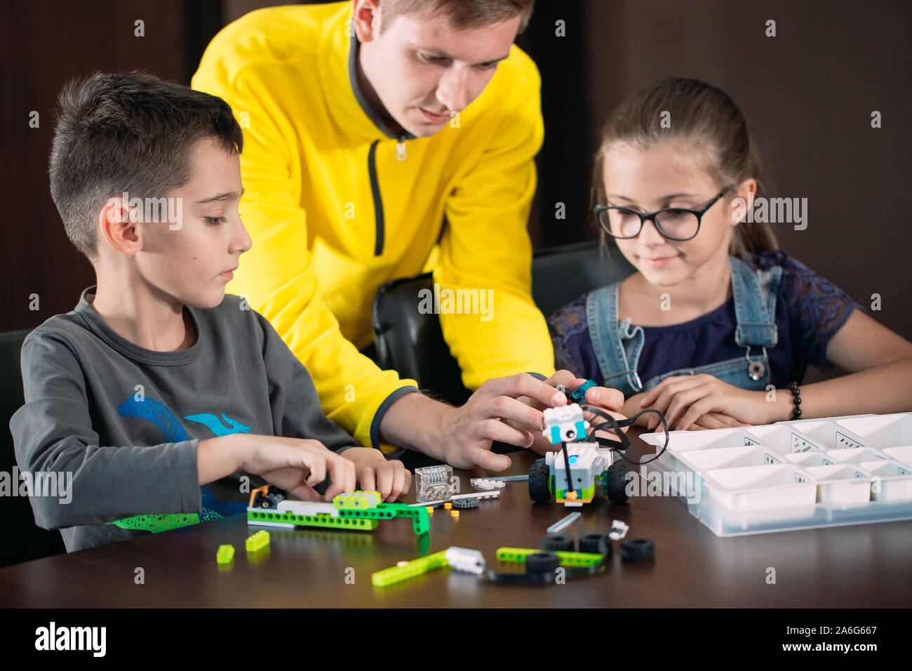 I ragazzi creando robot con insegnante. Sviluppo precoce, bricolage, innovazione, tecnologia moderna nozione Foto Stock
