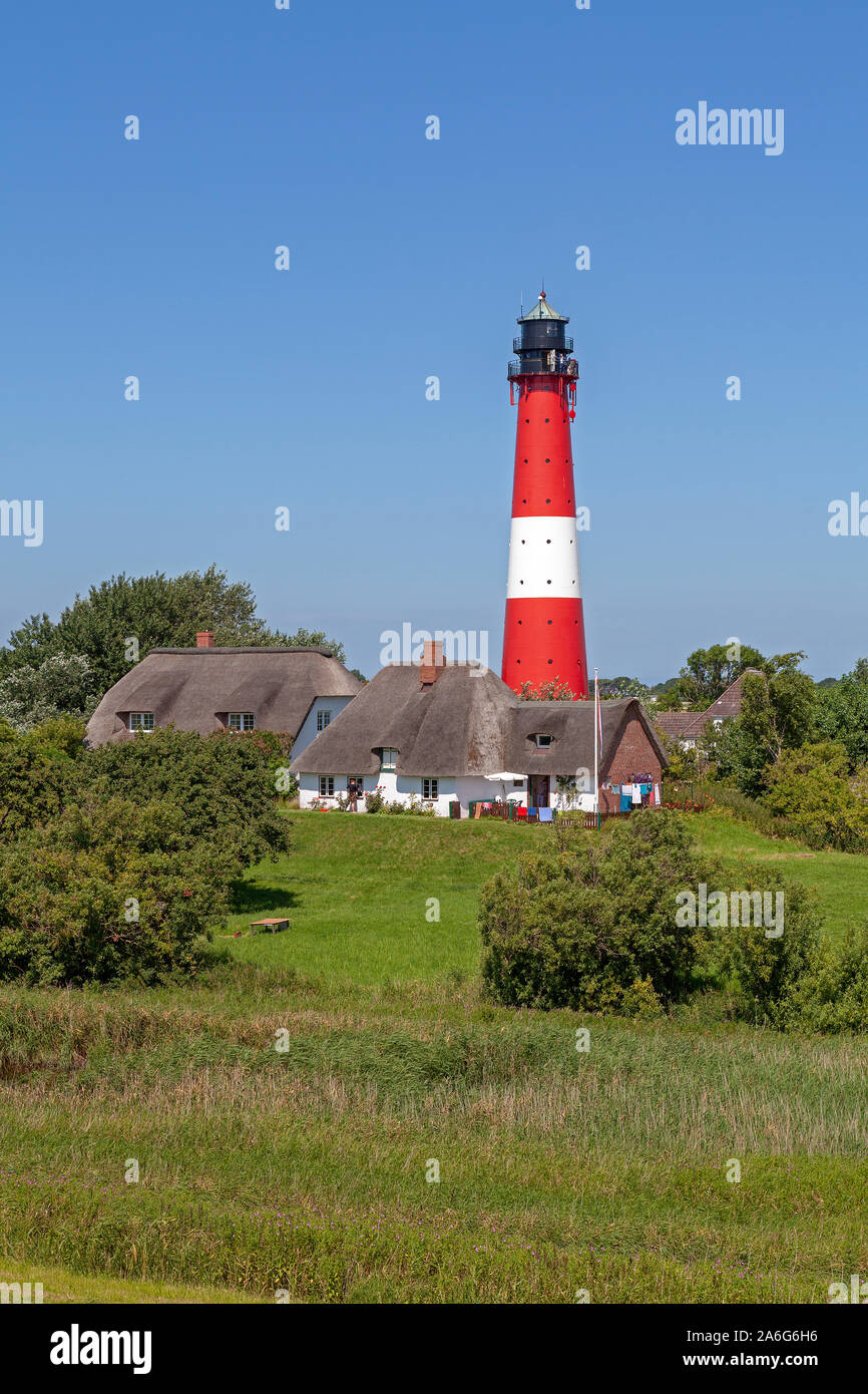 Case in paglia e il faro di isola di Pellworm in Nord Friesland, Schleswig-Holstein, Germania. Foto Stock