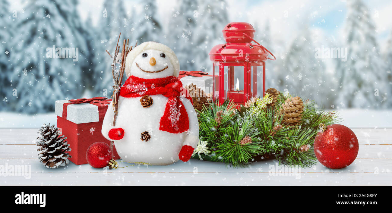 Carino il Natale Capodanno scena con un pupazzo di neve, doni, lanterna, sfere, coni e rami di abete. Inverno, la neve e gli alberi in background. Foto Stock