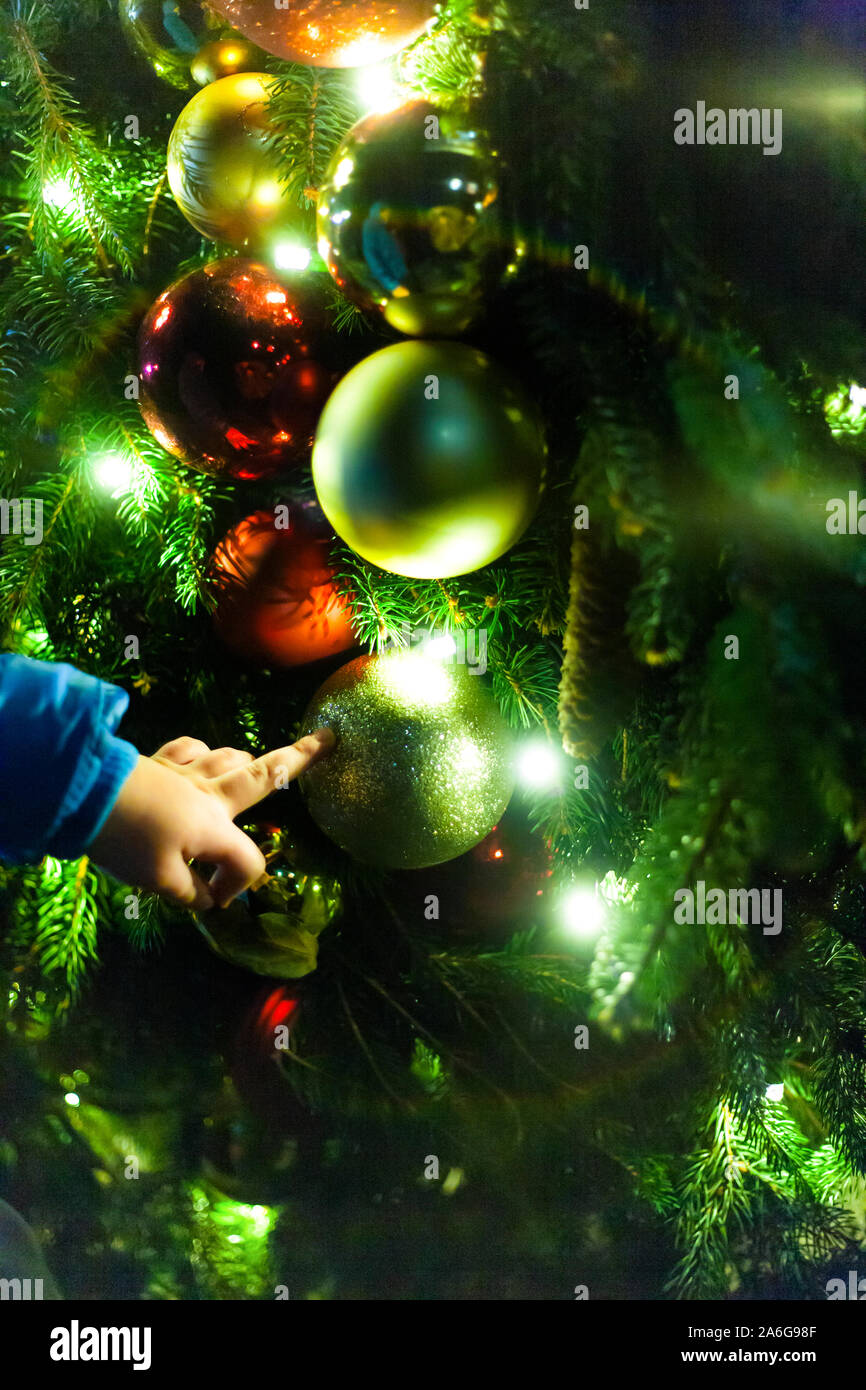 Il bambino gioca palla di Natale ornamenti.. Decorazione di natale su sfondo nero. Atmosfera natalizia. Un atmosfera di amore, di speranza, pace, gioia. Foto Stock