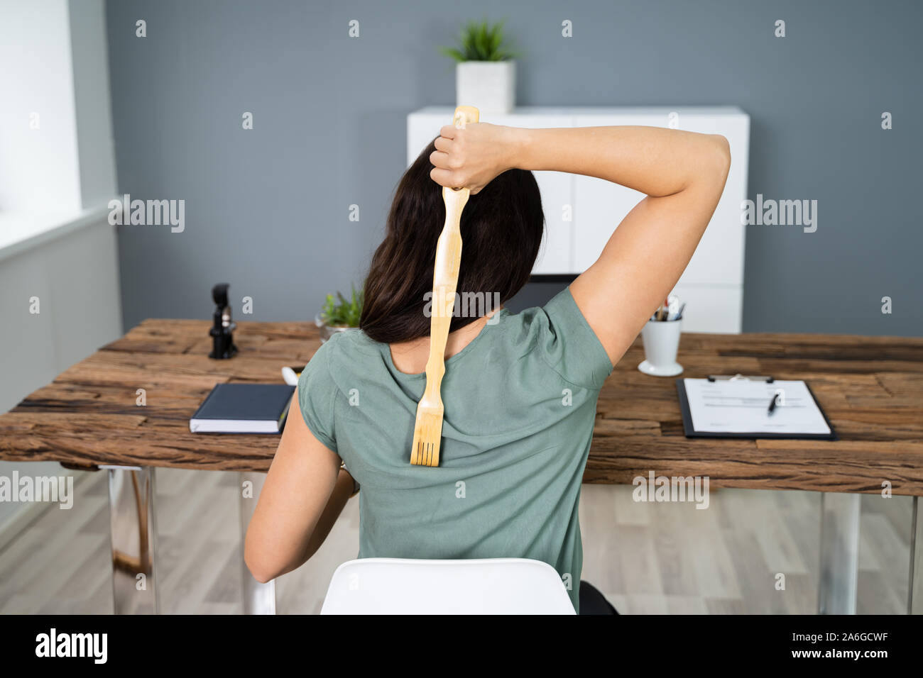 Giovane donna utilizzando Torna Scratcher in ufficio Foto Stock