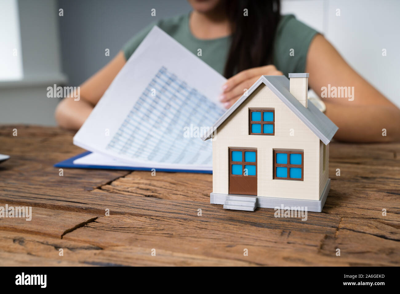 Immagine ritagliata di imprenditrice facendo il calcolo dal modello di casa sul tavolo Foto Stock