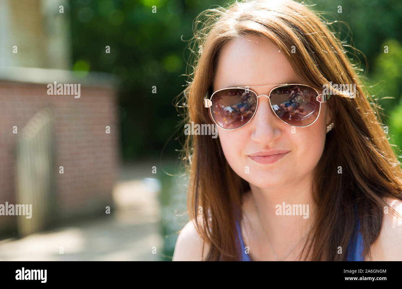 Una bella ragazza in posa per una foto in un bellissimo vestito blu su di una splendida giornata d'estate Foto Stock
