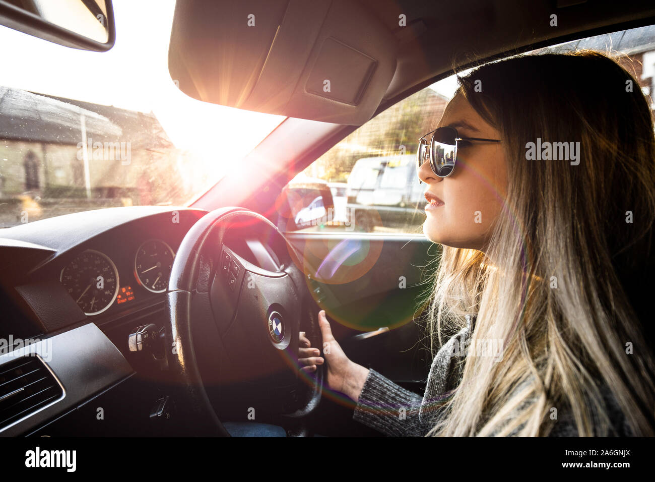 Una giovane donna alla guida di una BMW Serie 5 automobile indossando occhiali  da sole in una calda giornata di sole Foto stock - Alamy
