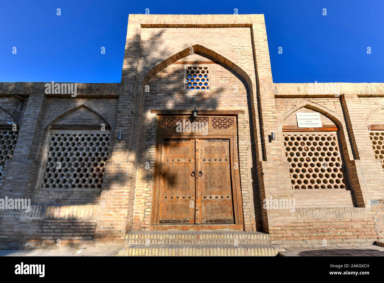 La facciata della antica Caravanserai Ahmadjon, secolo XIX, con intagliata in legno porta a Bukhara, Uzbekistan. Foto Stock