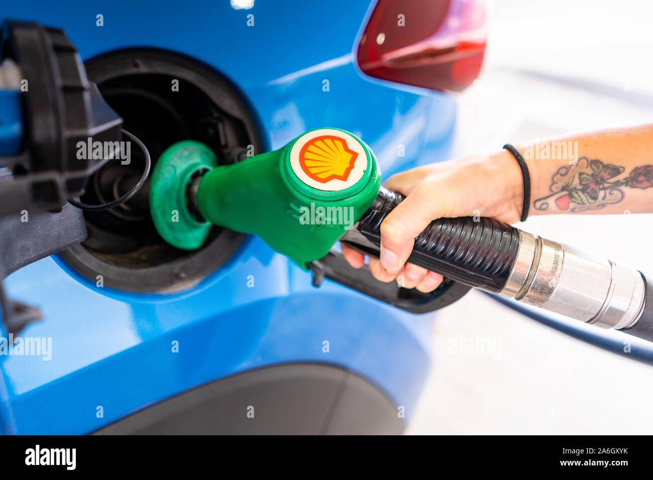 Un giovane slim donne con capelli viola si riempie la sua auto con benzina senza piombo, il distributore di benzina Shell Foto Stock