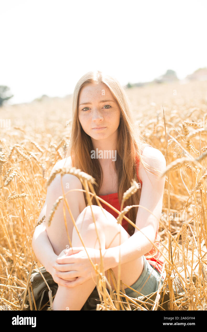 Una bella giovane ragazza adolescente avente un servizio fotografico in un campo di agricoltori in una calda giornata di sole in campagna, il bambino in campagna REGNO UNITO Foto Stock