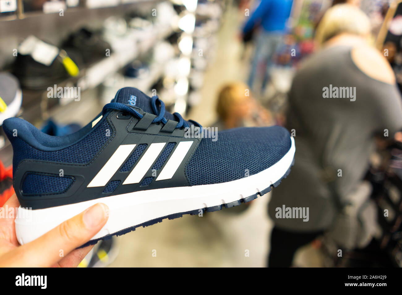 Una nuova coppia di blu Adidas trainer detenute da un uomo in negozio Foto  stock - Alamy