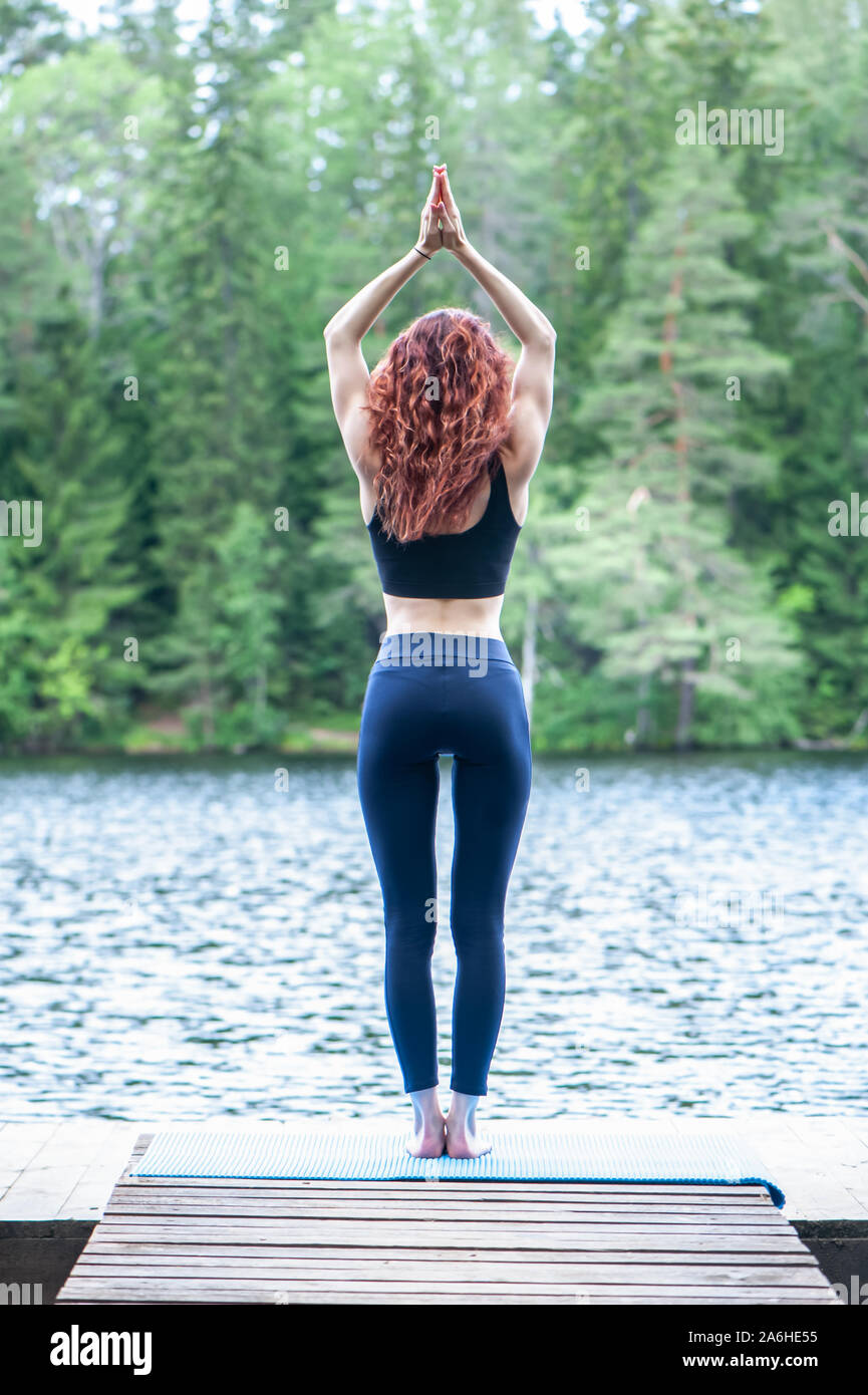 Ragazza giovane la pratica dello yoga nella natura sul lago. Femmina di felicità. Concetto di vita sana e naturale equilibrio Foto Stock