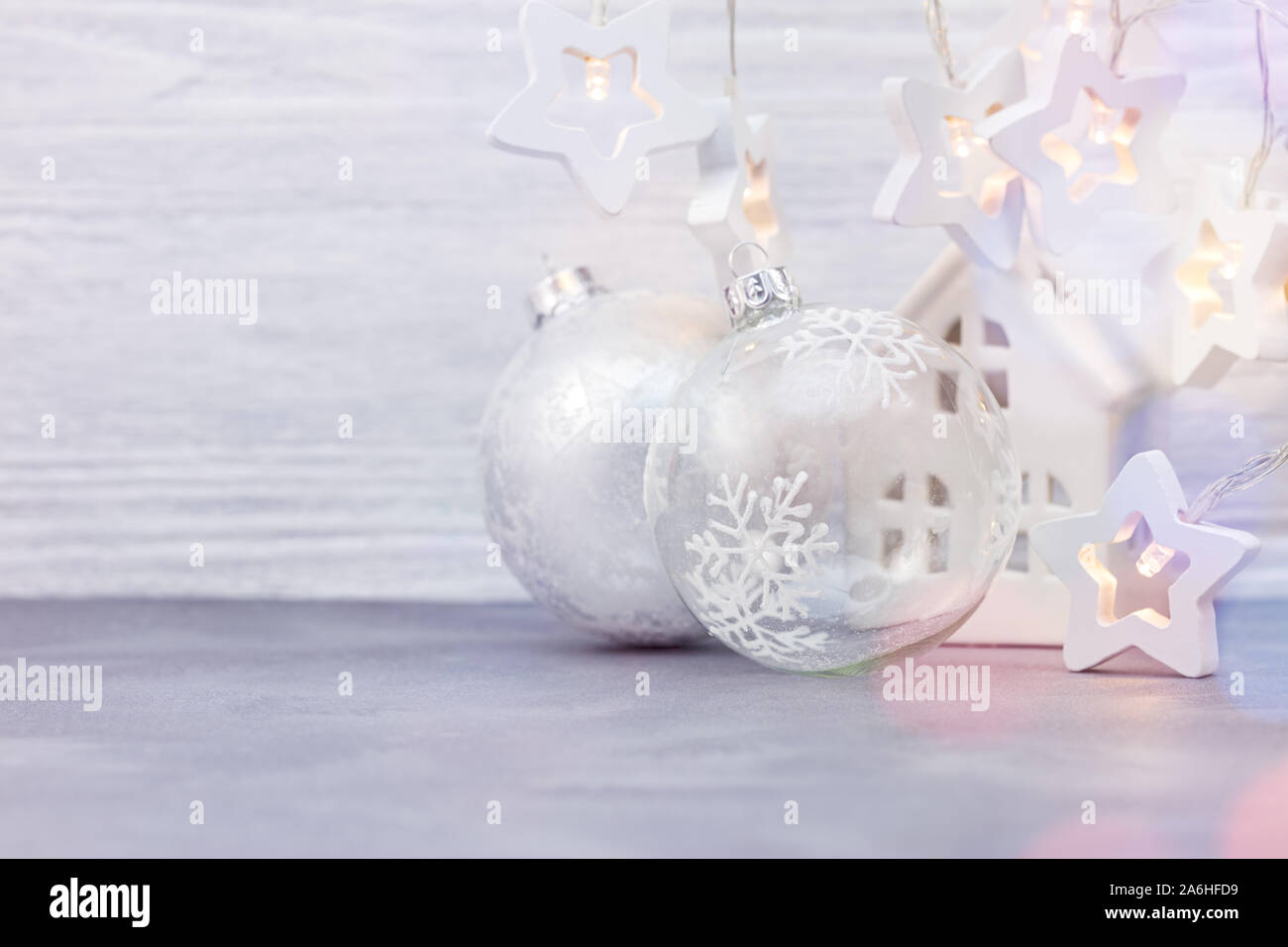 Vetro albero di natale sfere, stella decorativa ghirlanda di luci e piccola casa giocattolo sul bianco sullo sfondo di legno Foto Stock