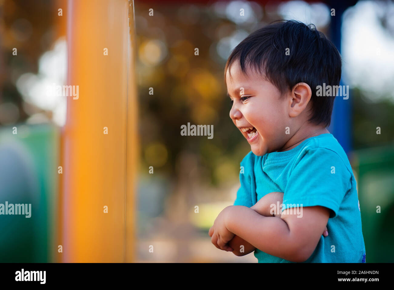 Ragazzo giovane ride molto e tenendo le braccia insieme durante il gioco in una giungla palestra. Foto Stock