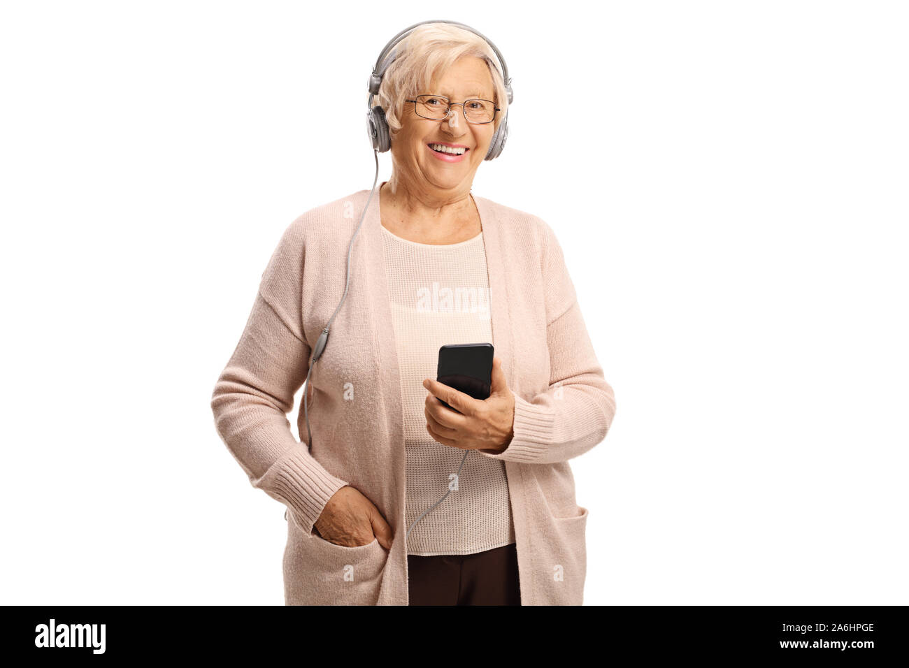 Donna anziana ascoltando musica su cuffie collegato a un telefono cellulare isolato su sfondo bianco Foto Stock