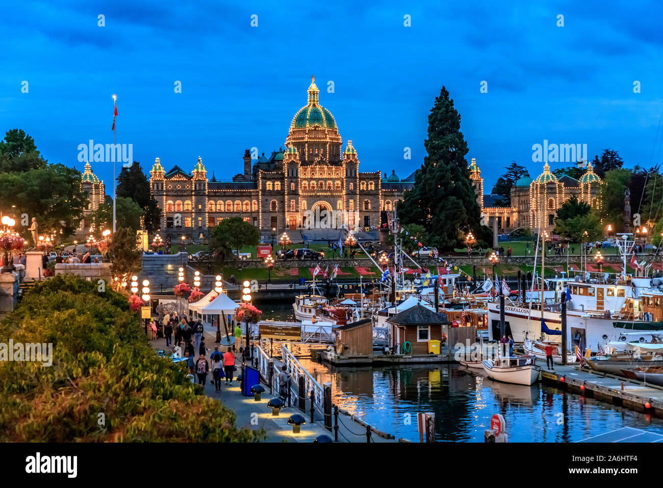 Il palazzo del parlamento in Victoria, British Columbia, Canada, illuminate al tramonto con il porto e le barche in primo piano Foto Stock