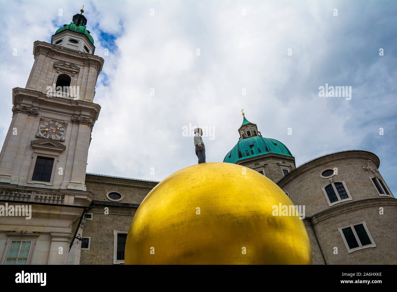 Stephan Balkenhol - Sphaera, una scultura di un uomo su una sfera dorata su Kapitelplatz nella città di Salisburgo, Austria. Cattedrale edificio in background. Foto Stock