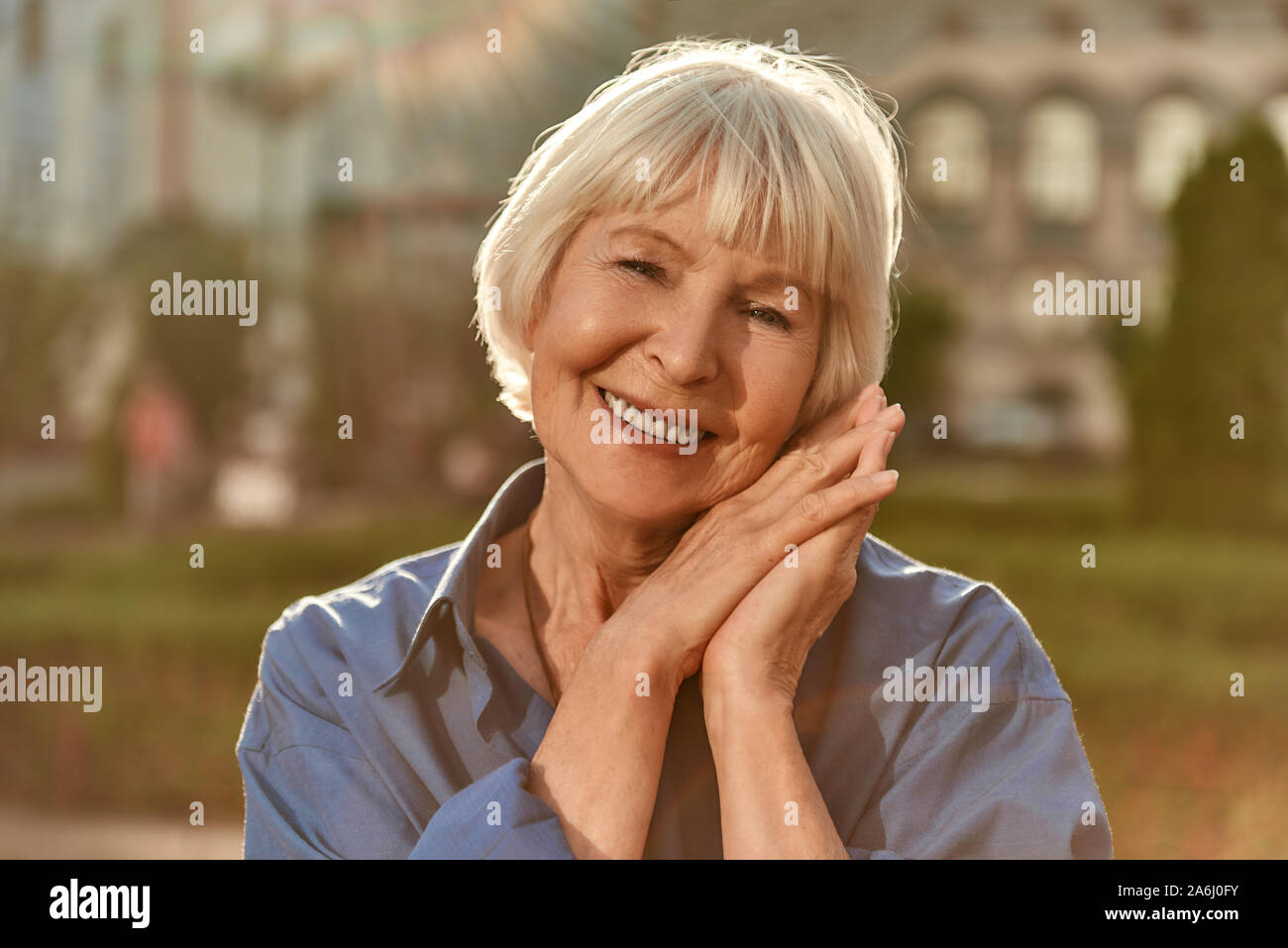 Età è solo un numero. Ritratto di bella e felice senior donna che guarda la fotocamera e sorridere mentre in piedi all'aperto in una giornata di sole Foto Stock