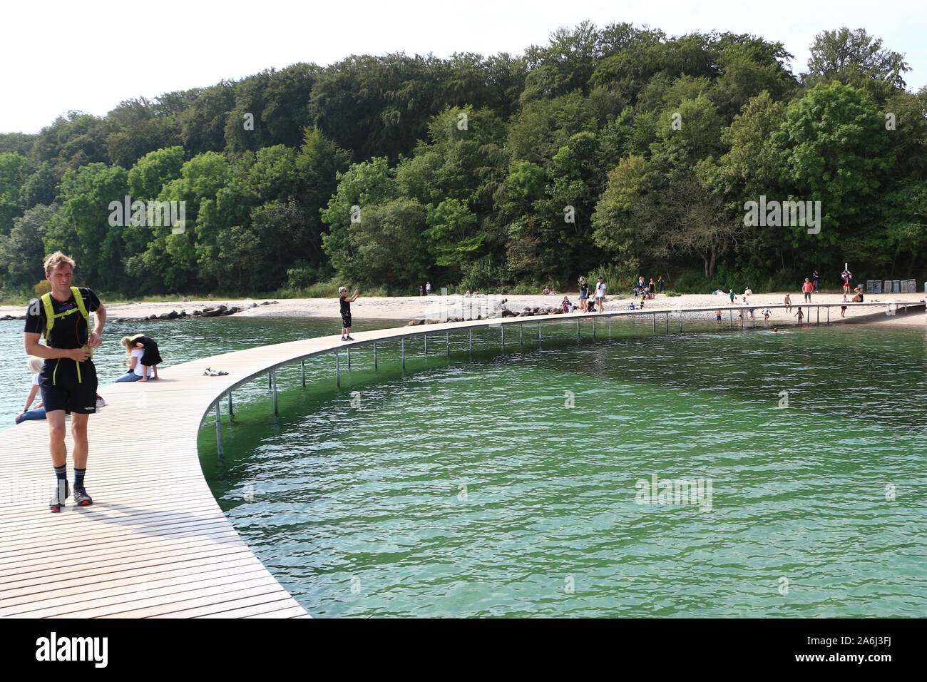 La gente a piedi dal Ponte di infinita (Den Uendelige Bro) - a forma di cerchio molo in legno costruita su un mare di Aarhus Bay su di una spiaggia di Varna/Ballehage Beach, creato dall'architetto Niels Povlsgaard e Johan Gjødes sono visti ad Aarhus in Danimarca il 30 luglio 2019 © Michal Fludra / Alamy Live News Foto Stock