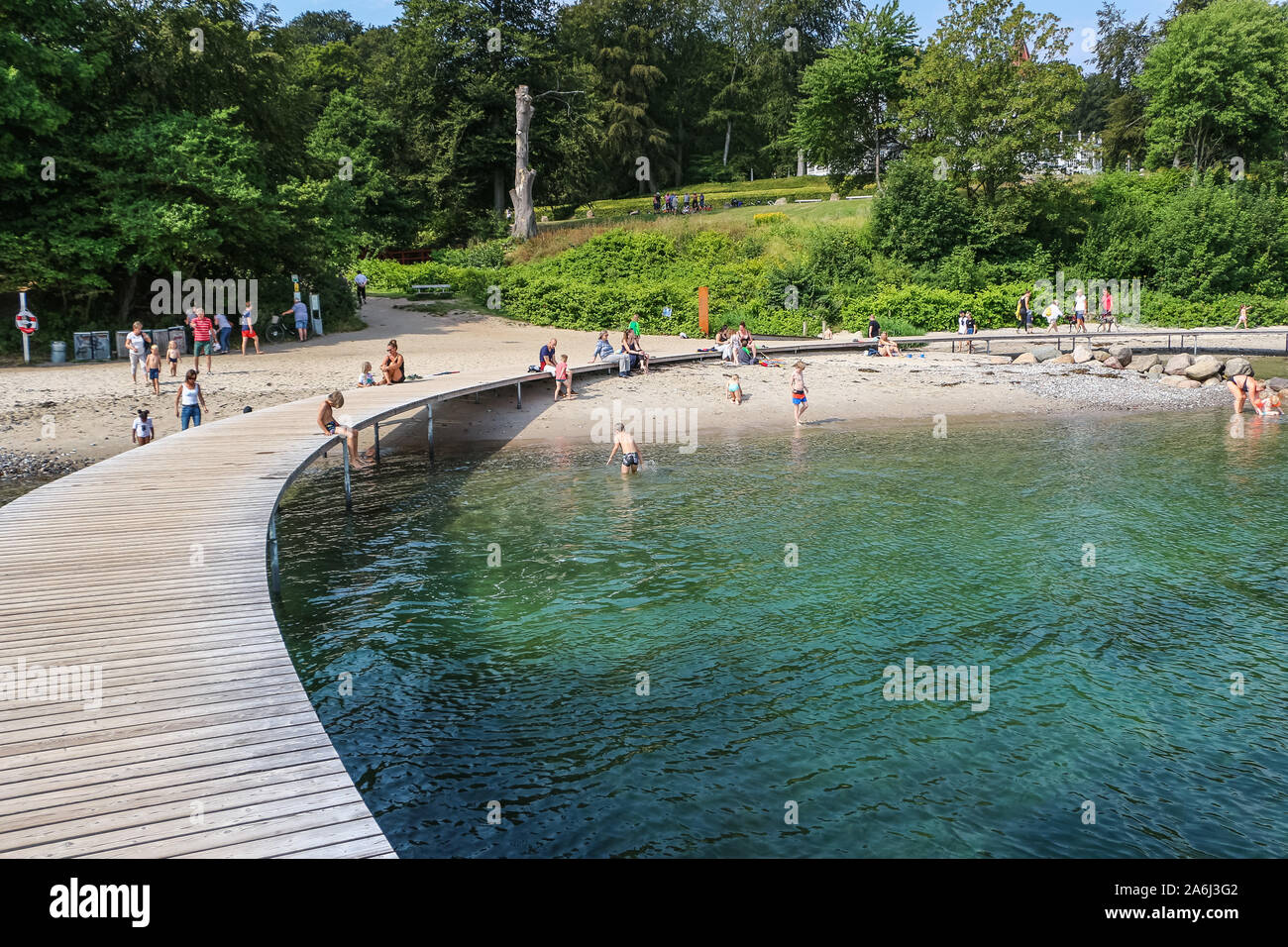 La gente a piedi dal Ponte di infinita (Den Uendelige Bro) - a forma di cerchio molo in legno costruita su un mare di Aarhus Bay su di una spiaggia di Varna/Ballehage Beach, creato dall'architetto Niels Povlsgaard e Johan Gjødes sono visti ad Aarhus in Danimarca il 30 luglio 2019 © Michal Fludra / Alamy Live News Foto Stock