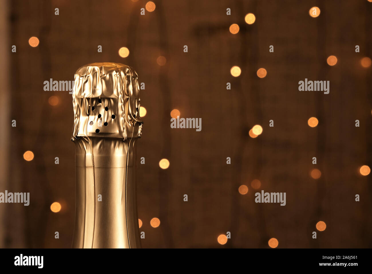 L'oro della bottiglia di champagne sulla marrone con sfondo sfocato ghirlanda di luci, il Natale o il messaggio di saluto per matrimoni, feste di sfondo, copia spazio per design e Foto Stock