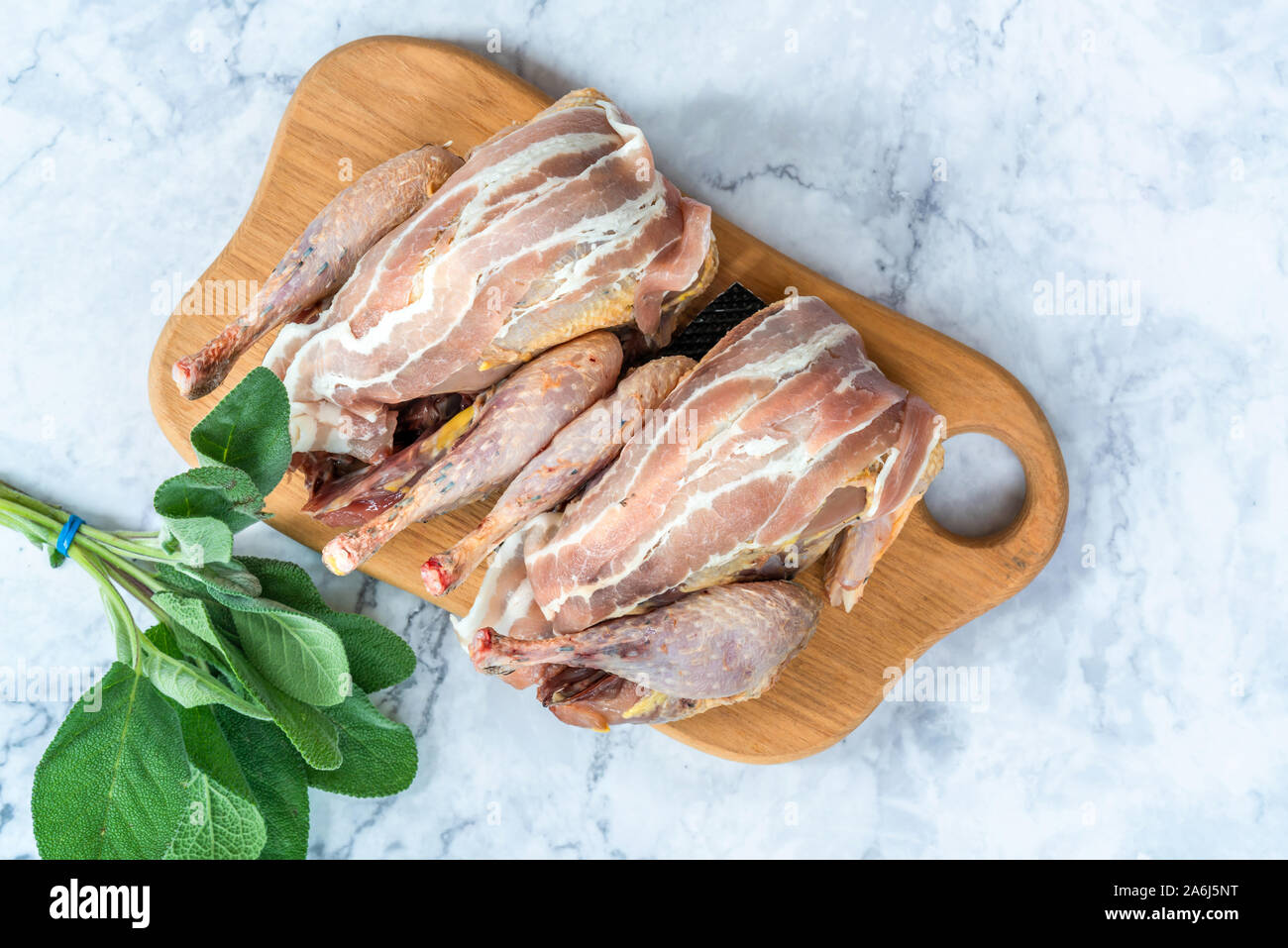 Due nuove materie fagiani avvolto in pancetta preparate per la cottura su tavola di legno - vista aerea Foto Stock