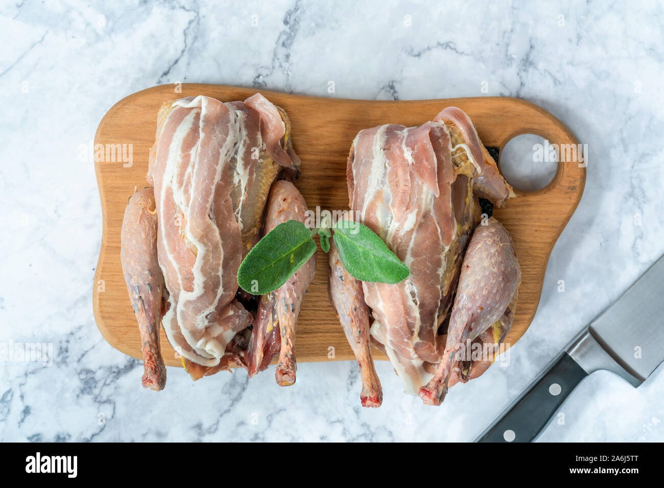 Due nuove materie fagiani avvolto in pancetta preparate per la cottura su tavola di legno - vista aerea Foto Stock