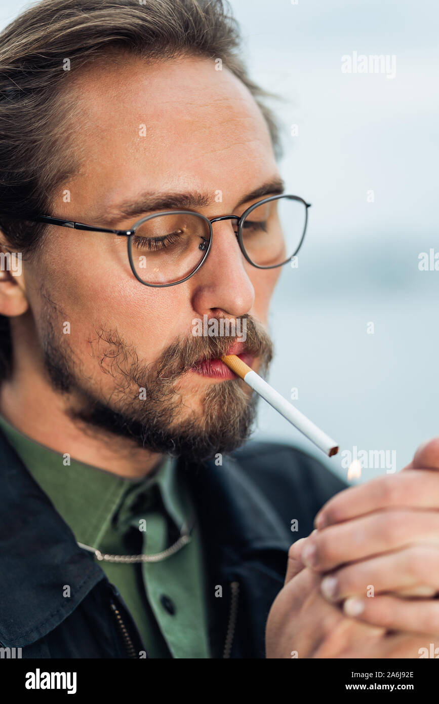 Foto di un giovane uomo di illuminazione di un cigarrete Foto Stock