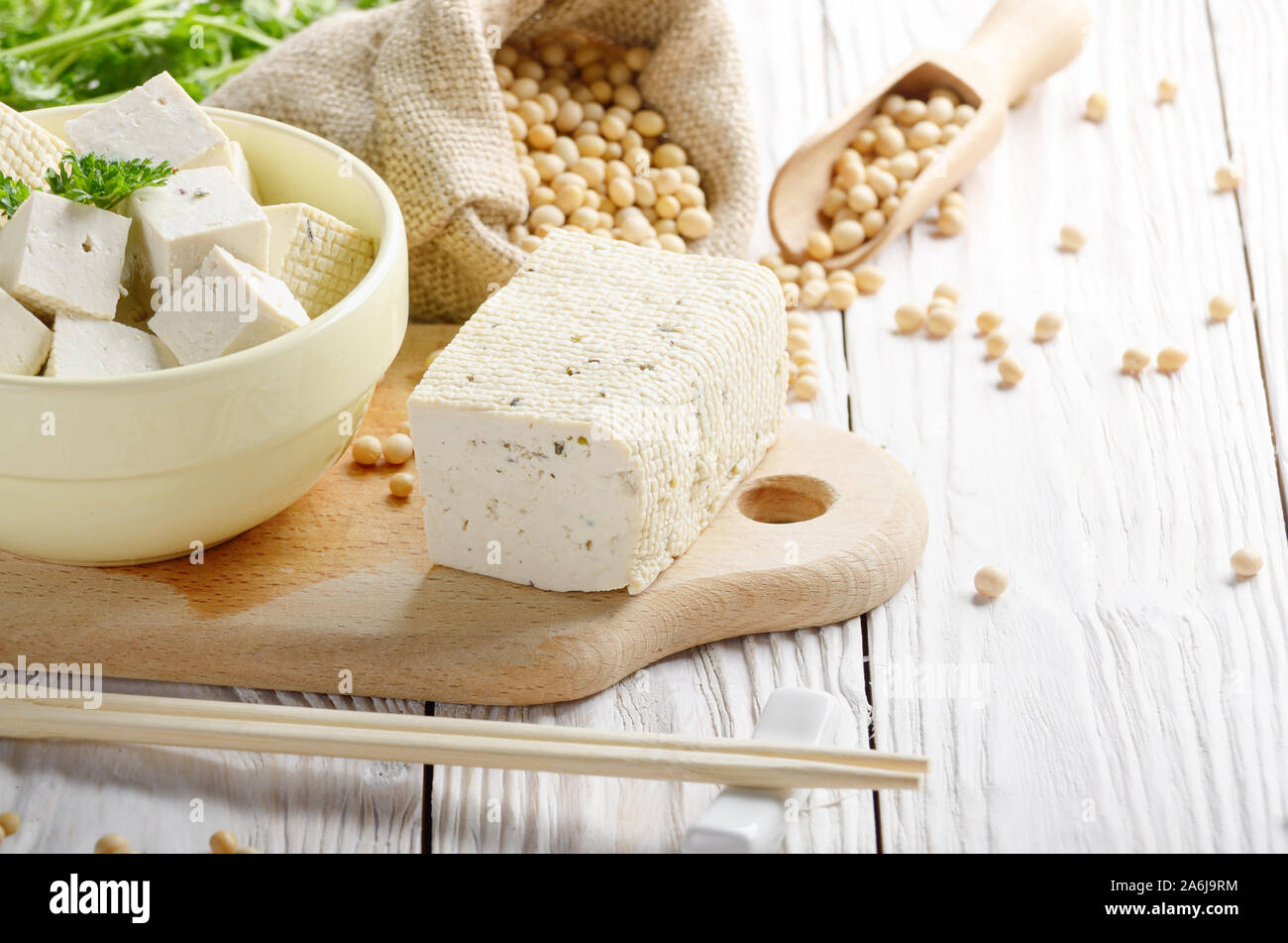 Fagiolo di Soia Curd tofu in vaso di creta e nel sacco di canapa su bianco cucina in legno tavolo. Non a base di latte sostituto alternativo per il formaggio. Posto per il testo Foto Stock