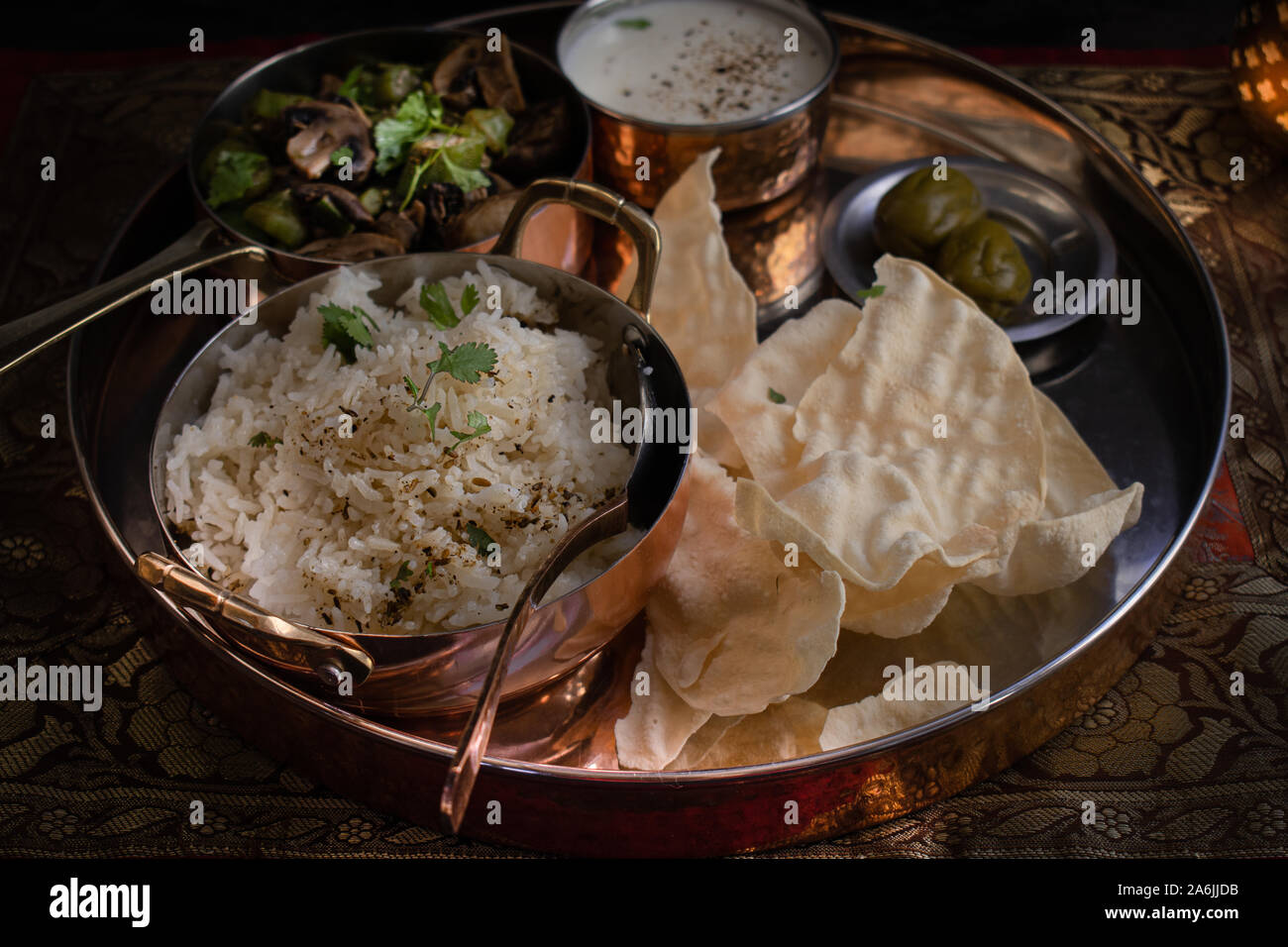 Thali- indiano piatto vegetariano. Le ciotole di riso speziato, okra e fungo curry, latticini, papad Foto Stock