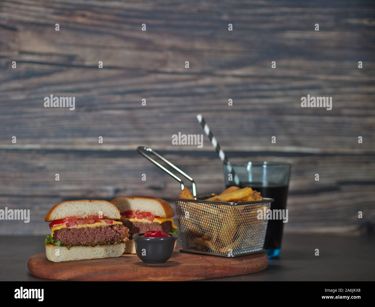 Vegan impianto basato burger tagliato a metà con patate fritte servite su vassoio in legno Foto Stock