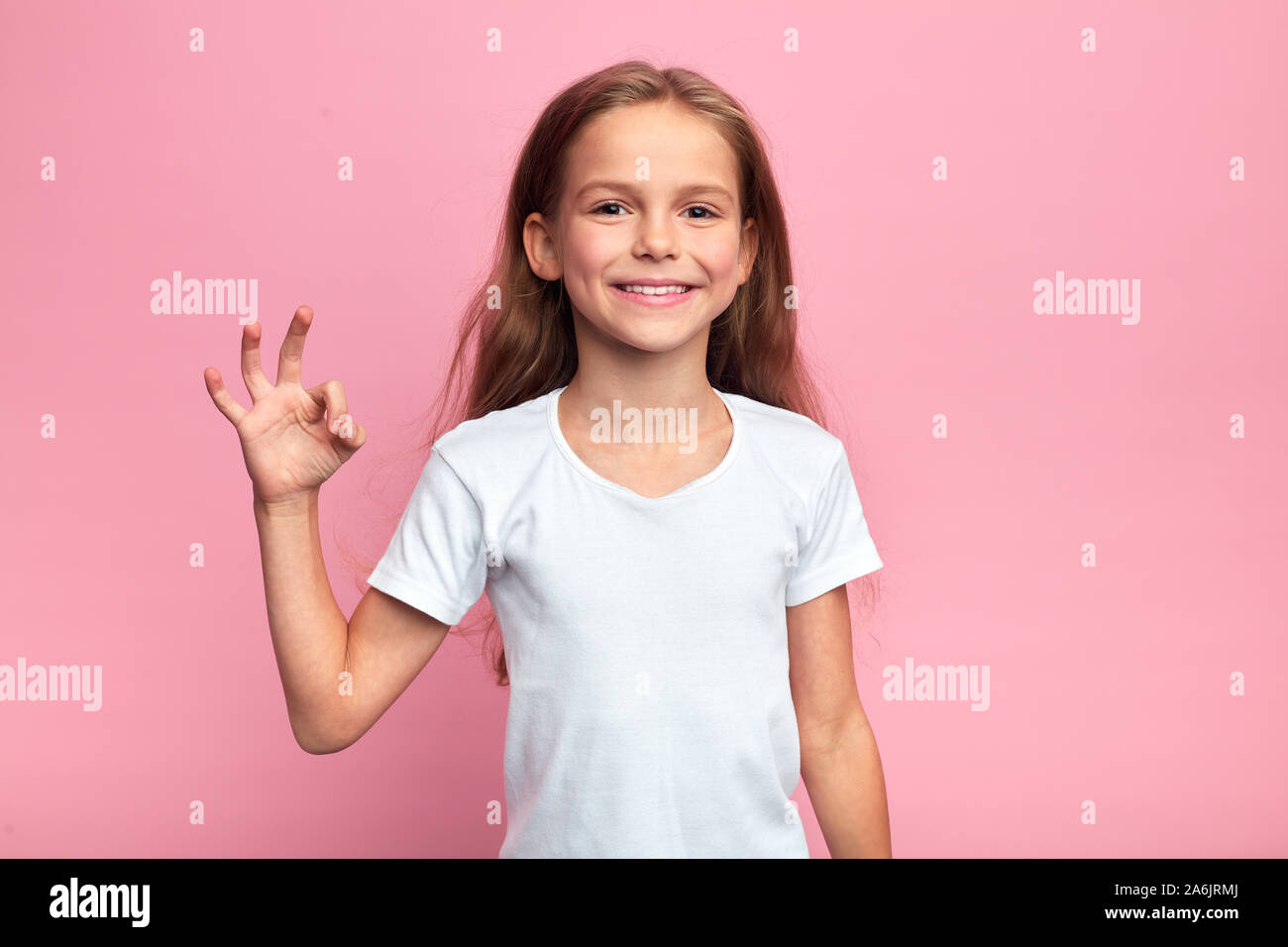 Allegro bella ragazza bionda che mostra bene segno, close up ritratto, corpo languge, accordo, tutto è ok, andare, isolato sfondo rosa, st Foto Stock