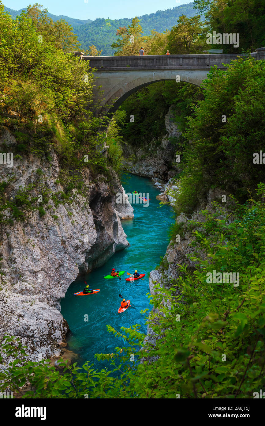 Interessante il rafting e il kayak luoghi. Active kayakers pagaiando sul colore smeraldo Soca river, sotto il vecchio ponte in pietra vicino a Kobarid, Triglav Nationa Foto Stock