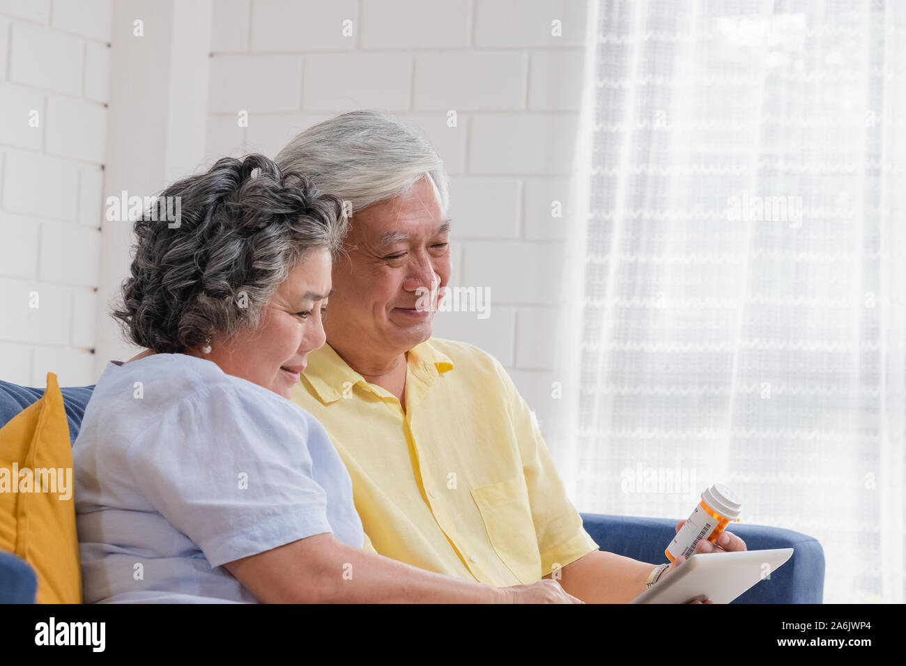 Asian coppia senior utilizzano tablet video conferenza con il medico circa la pillola comodamente seduti sul divano di casa,senior imparare a utilizzare la tecnologia.invecchiamento a home Foto Stock