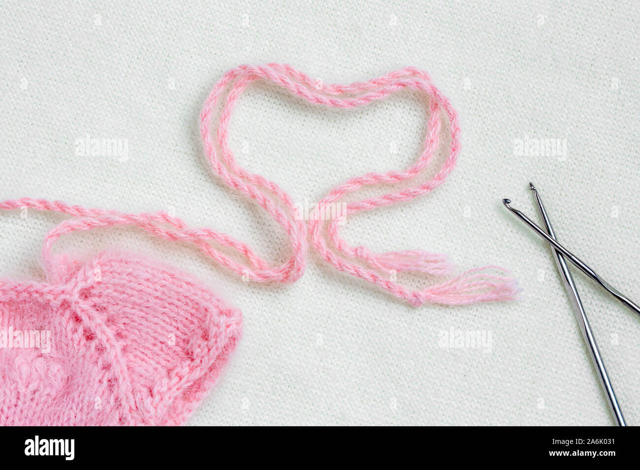 Vestiti del bambino per il neonato in rosa pastello su lana bianca dello  sfondo. Cuore di colore rosa uncinetto Filati. Il resto, la maternità, la  famiglia Foto stock - Alamy