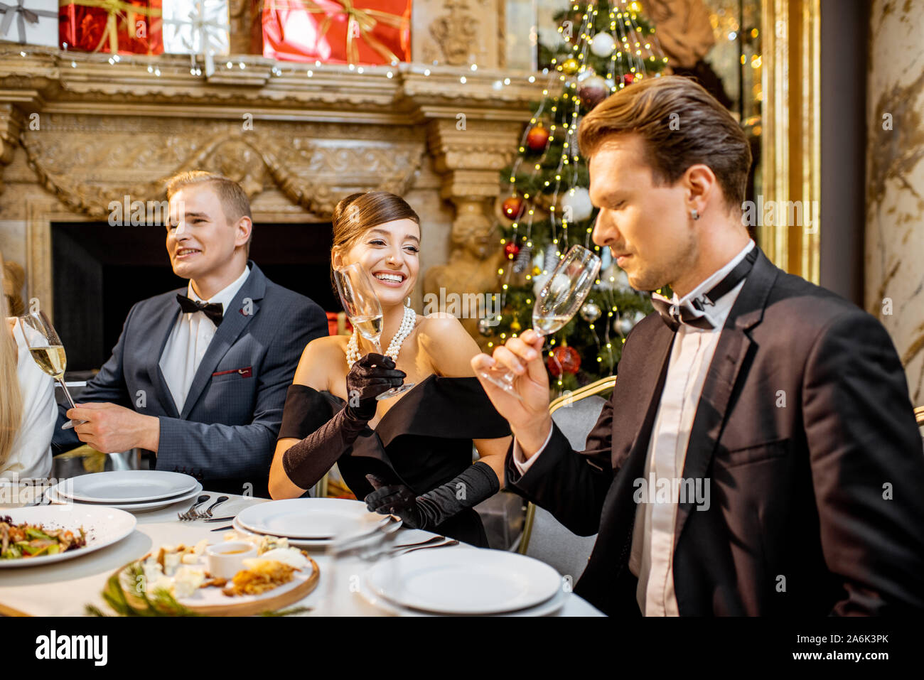 Elegantemente vestito gruppo di persone aventi una cena di gala in una tavola ben servita, per celebrare il nuovo anno di vacanza presso il ristorante di lusso Foto Stock