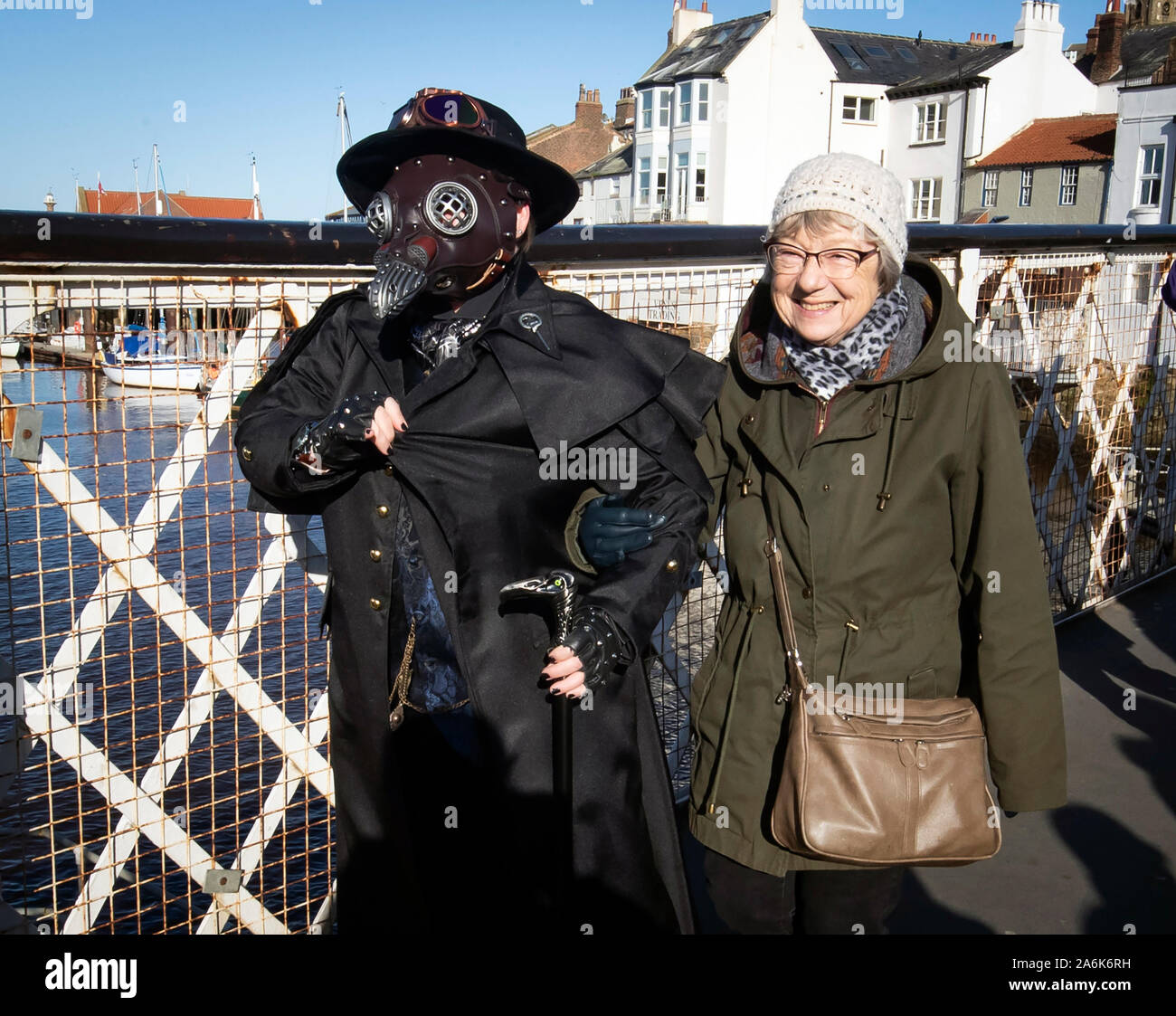 Una donna links bracci con un goth come essi frequentano la Whitby Goth Weekend a Whitby, nello Yorkshire, come centinaia di goti discendere sulla cittadina balneare dove Bram Stoker trovò ispirazione per 'Dracula' dopo un soggiorno in città nel 1890. Foto di PA. Picture Data: domenica 27 ottobre, 2019. La Whitby Goth Weekend è un semestrali di musica alternativa festival organizzato da Jo Hampshire costituito da due notti di bande dal vivo presso le sedi in tutta la città. Le origini del festival sono in una riunione di circa quaranta di Ms Hampshire il pen-pals in 1994. L'evento è cresciuto fino a diventare uno dei più famosi del mondo. goth Foto Stock