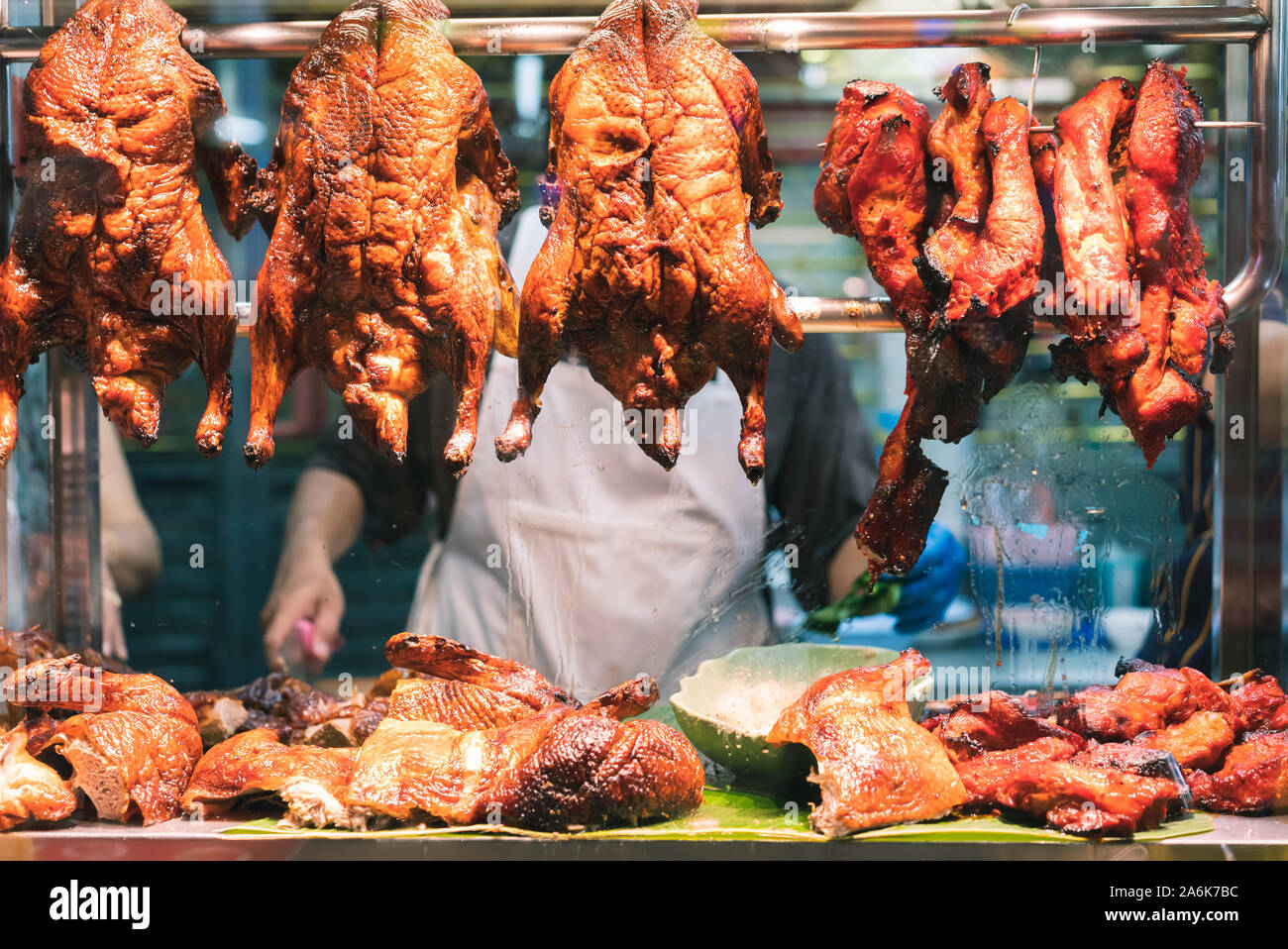 Arrostito croccante anatra cinese e la carne di maiale appeso dal finestrino di un cibo di strada del mercato notturno in stallo - asiatico marinato la carne e il pollame sul display in un ristorante locale - la cucina, viaggi e delicatezza concept Foto Stock