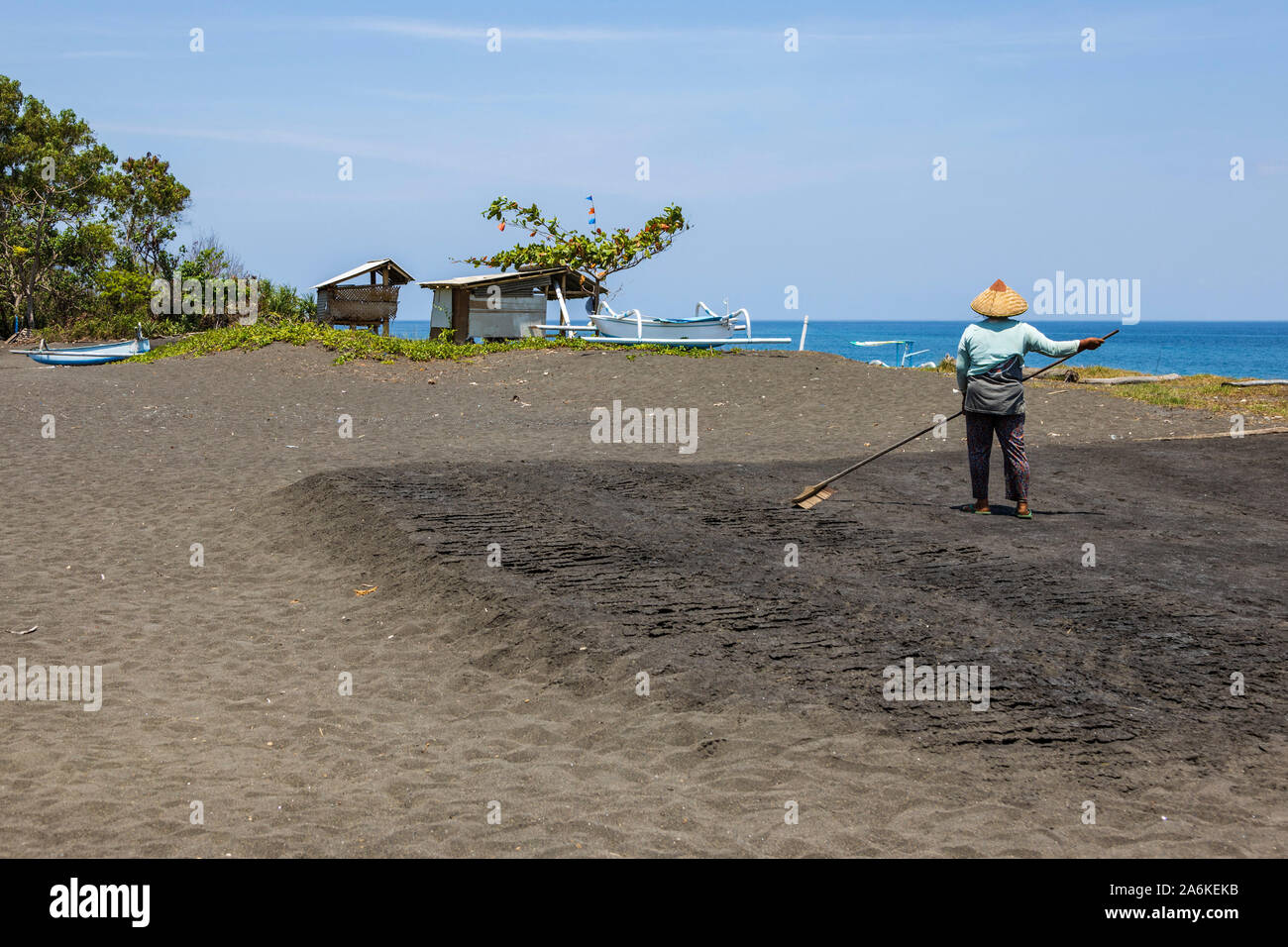 Donna rastrellatura beach per produrre il sale di mare nella baia di Amuk, Bali Orientale, Indonesia, Asia sud-orientale, Asia Foto Stock