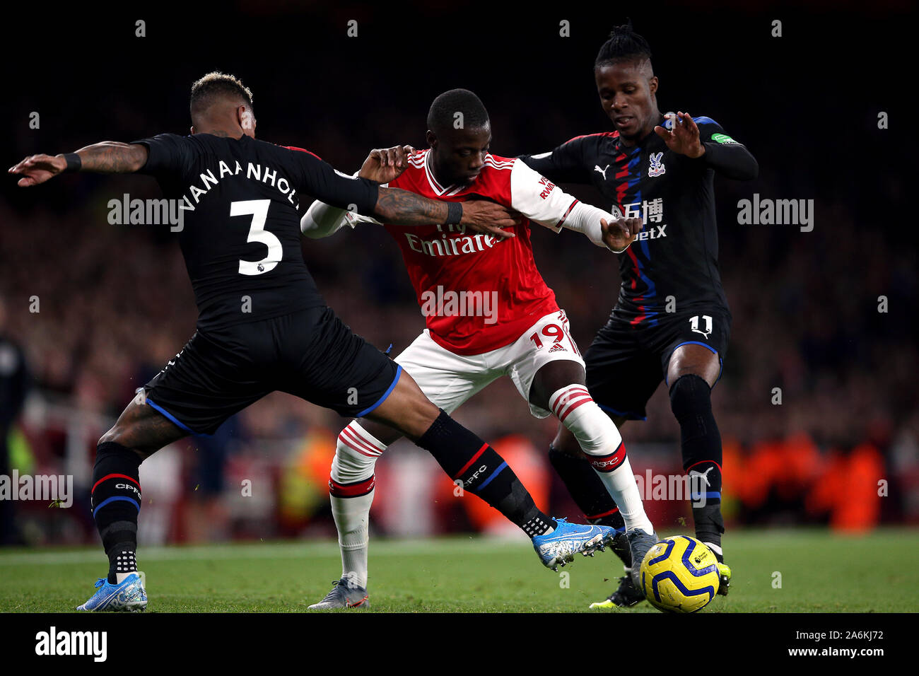 Dell'Arsenal Nicolas Pepe battaglie per la palla con il Palazzo di Cristallo Patrick van Aanholt e Crystal Palace di Wilfried Zaha (a destra) durante il match di Premier League a Emirates Stadium di Londra. Foto Stock