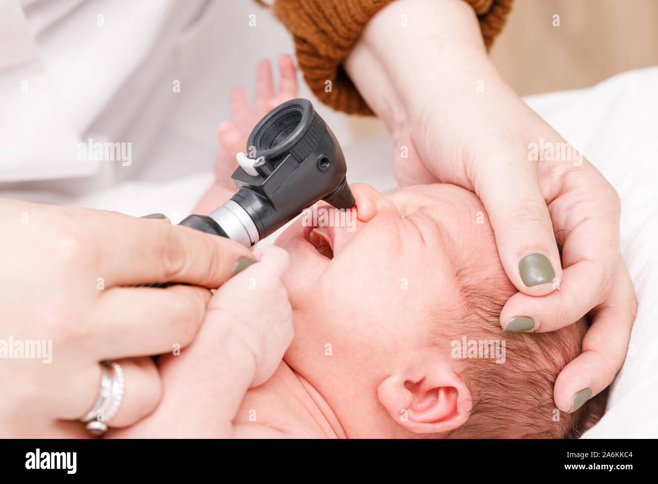 Pediatra esamina due settimane vecchio bimbo di naso in clinica pediatrica. Medico utilizzando otoscopio (auriscope) per verificare il passaggio nasale. Neonato ENT check-up con Foto Stock